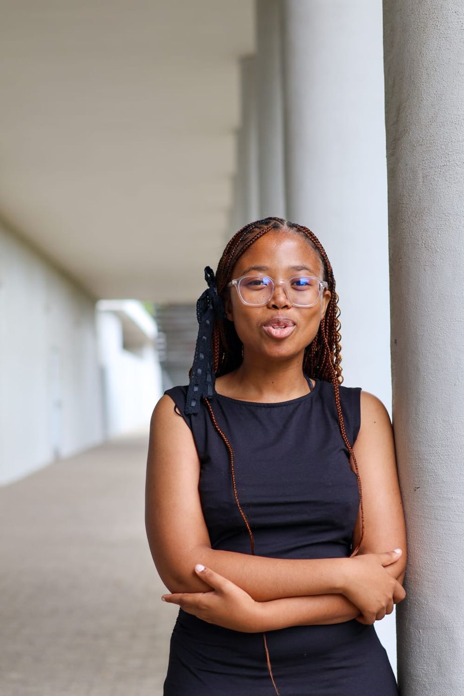 Okuhle leaning against a pillar with her arms folded, mid-laugh
