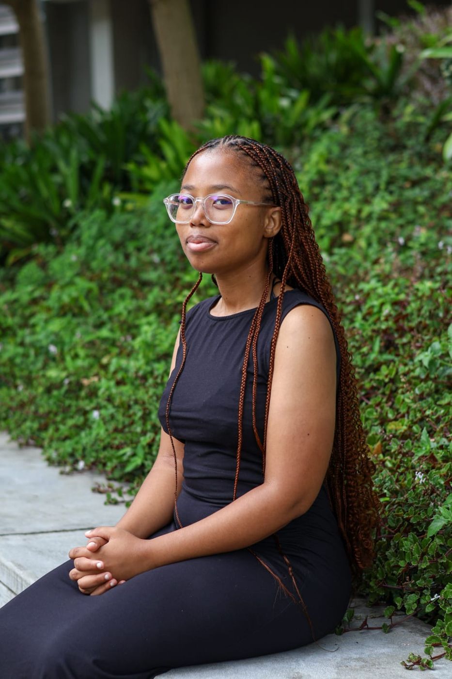 Okuhle sitting beside a bank of green groundcover, looking at the camera